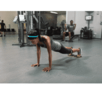 אישה מאמנת פלנק בחדר כושר עם דיסקיות החלקה